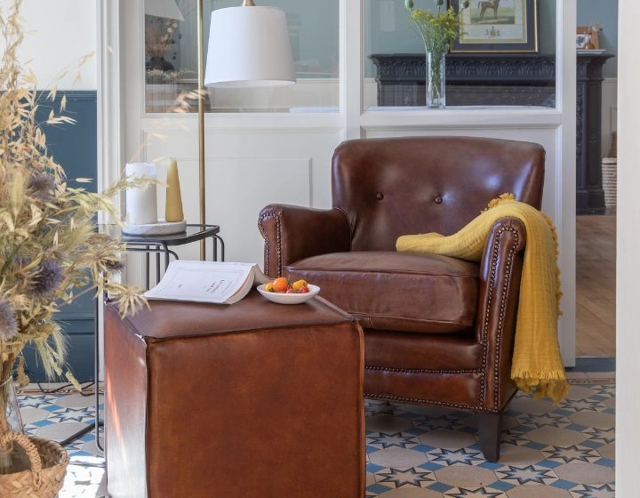 Fauteuil club cuir marron soutenu accoudoirs cloutés